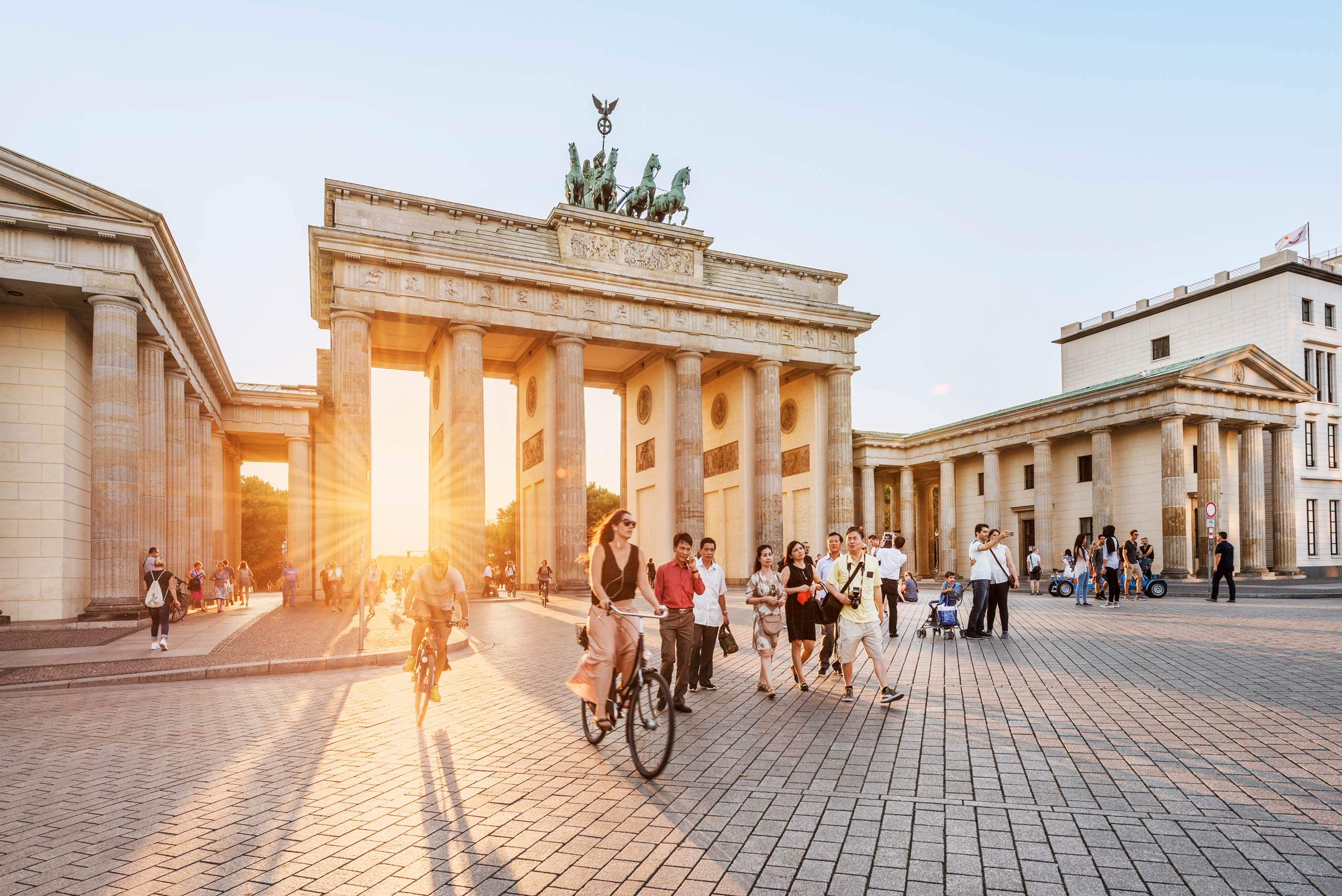 Radfahrer und Touristen vor dem Brandenburger Tor im Abendlicht 